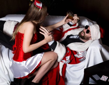 Karnaval kılık seksi kadın kadın hemşire sarhoş santa cümlecik, koltukta yalan çalışır onu uyandırmak