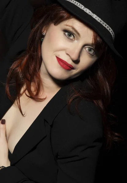 Krásná žena v černém klobouku a bundu na tmavém pozadí. — Stock fotografie