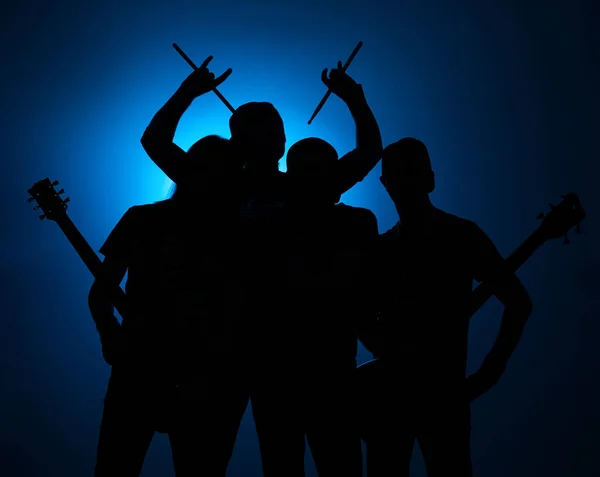 Banda de jóvenes músicos masculinos de pie con instrumentos sobre un fondo azul — Foto de Stock