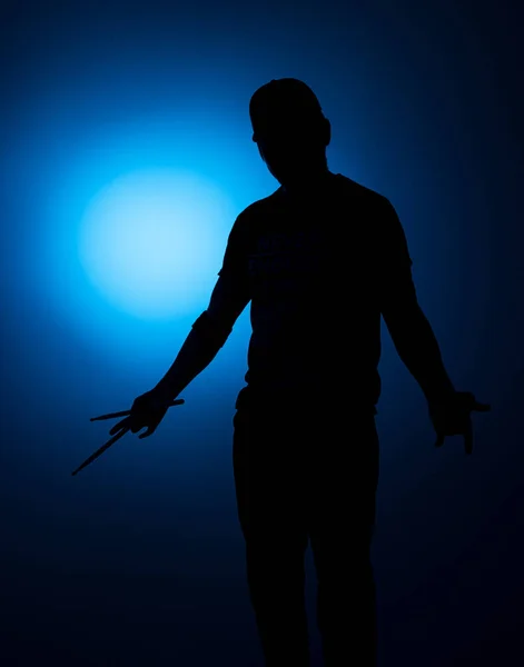 Silhouette Jeune batteur expressif avec batteur sur fond bleu — Photo