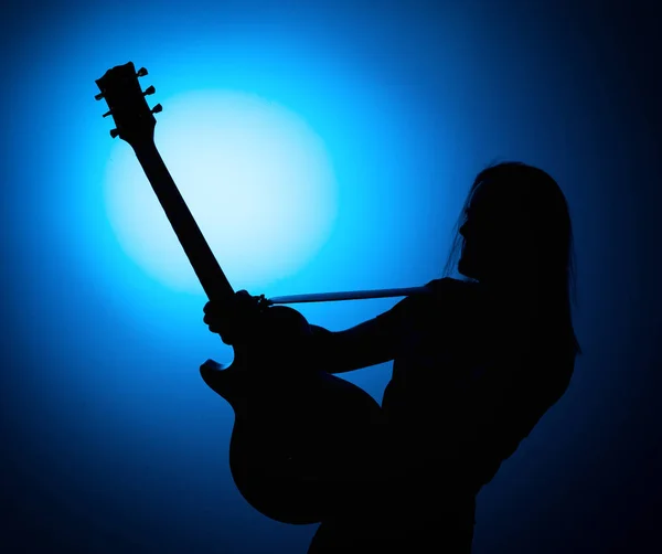 Silhueta guitarristas de uma banda de rock com guitarra sobre fundo azul — Fotografia de Stock