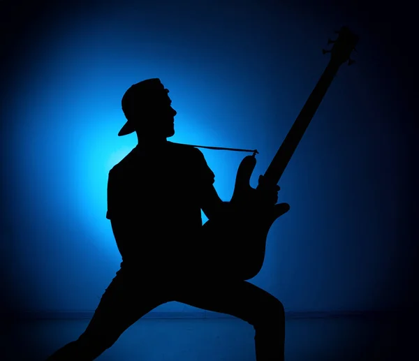 Silhouette guitarists of a rock band with guitar on blue background — Stock Photo, Image