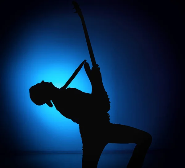 Silhouette guitarists of a rock band with guitar on blue background — Stock Photo, Image