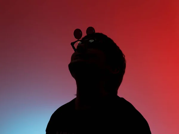 Silueta balancín hombre en un divertido gafas posando sobre fondo rojo — Foto de Stock