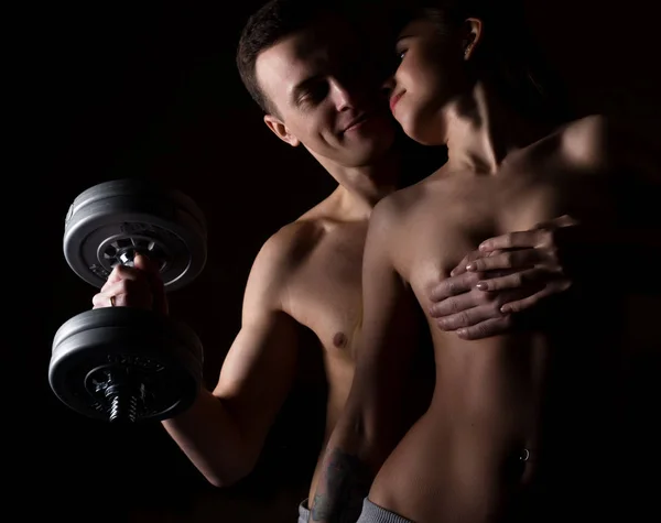 Beautiful young sporty sexy couple showing muscle on a dark background — Stock Photo, Image