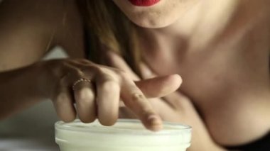 bir kedi gibi süt içme dantel maskeli genç seksi kadın. gülümseyen kız bir parmak bir kase yoğurt dips