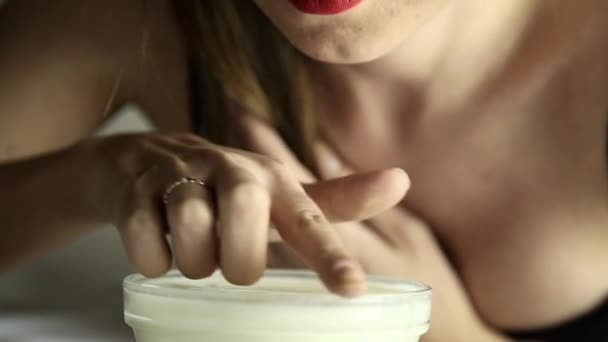 Νέοι σέξι γυναίκα σε μια δαντέλα μάσκα πίνοντας γάλα όπως μια γάτα. χαμογελαστό κορίτσι βουτάει ένα δάχτυλο σε ένα μπολ με γιαούρτι — Αρχείο Βίντεο