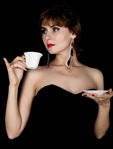 De retro vrouwelijke schoonheid model met professionele make-up, het drinken van koffie of thee. de vintage vrouw mode op een donkere achtergrond — Stockfoto