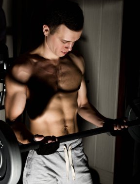 Darck arka plan üzerinde halter ile yakışıklı atletik erkek