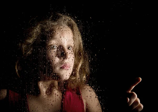 Μοναχική κοπέλα θλιβερό πίσω από το παράθυρο με σταγόνες. φοβισμένη νεαρή γυναίκα δείχνει κάτι — Φωτογραφία Αρχείου