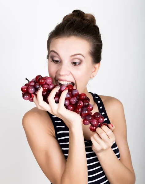 Jovem mulher sorridente segurando fresco cacho vermelho de uvas . — Fotografia de Stock