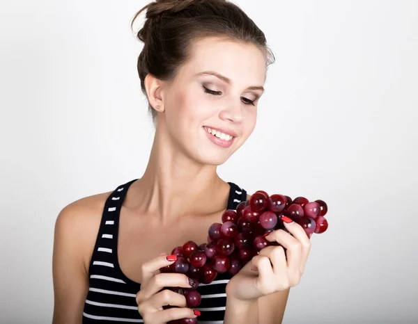 Joven mujer sonriente sosteniendo fresco racimo rojo de uvas . — Foto de Stock