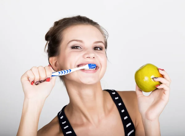 Retrato de una mujer joven sosteniendo una manzana y un cepillo de dientes, concepto de salud dental — Foto de Stock