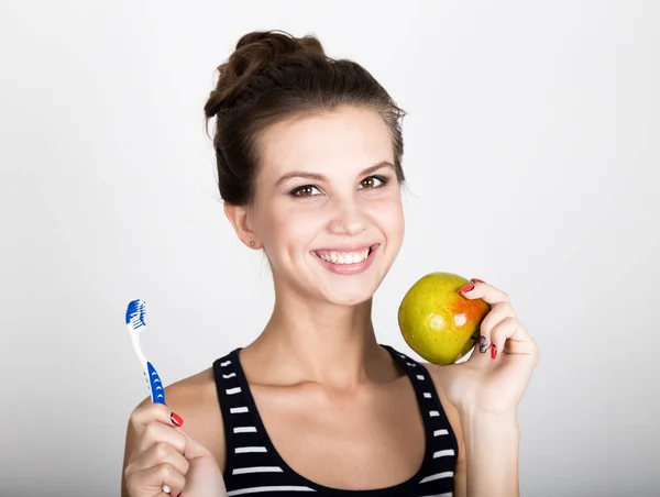 Retrato de una mujer joven sosteniendo una manzana y un cepillo de dientes, concepto de salud dental — Foto de Stock