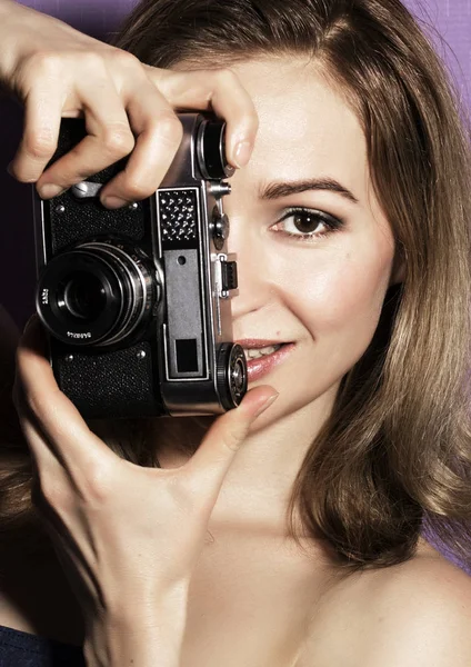 Stupito giovane bella donna tenendo la fotocamera e guardando avanti — Foto Stock