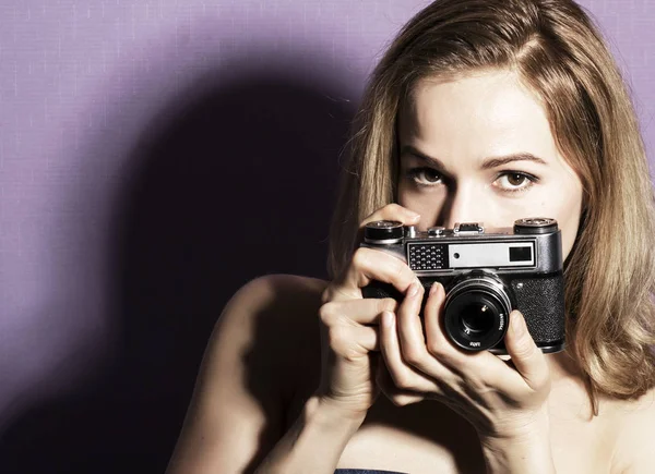 Sorprendido joven bonita mujer sosteniendo la cámara y mirando hacia el futuro — Foto de Stock