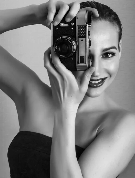 Amazed young pretty woman holding camera and looking ahead Stock Photo