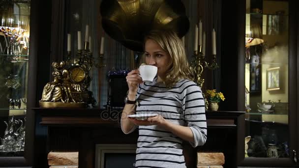 Portrét mladé ženy stends u krbu, happy usmívající se holka pije čaj — Stock video