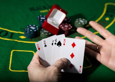 Casino fişi ve yeşil poker tablo arka planda, kaybeden kartların kombinasyonu tutan adam değerli bir yüzük