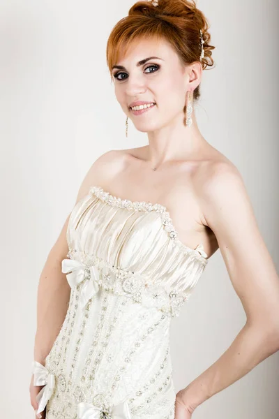 Schöne junge rothaarige Braut trägt weißes Hochzeitskleid mit professionellem Make-up und Frisur — Stockfoto