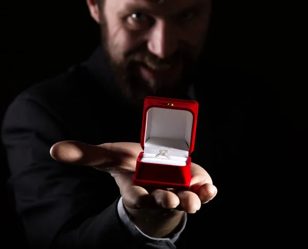 Skäggig man i kostym ger en ring i den röda rutan och uttrycker olika känslor på mörk bakgrund — Stockfoto