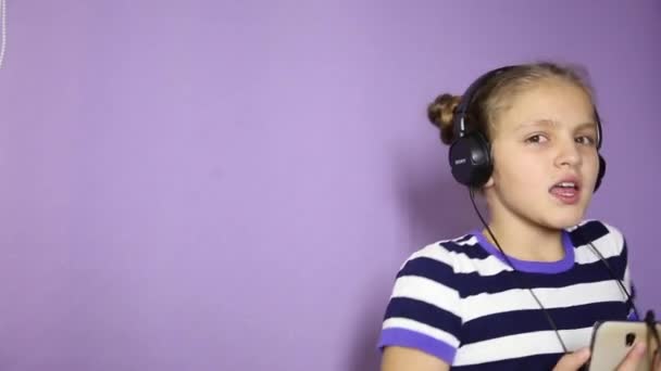 Young girl with pigtails listening music on headphones and dancing — Stock Video
