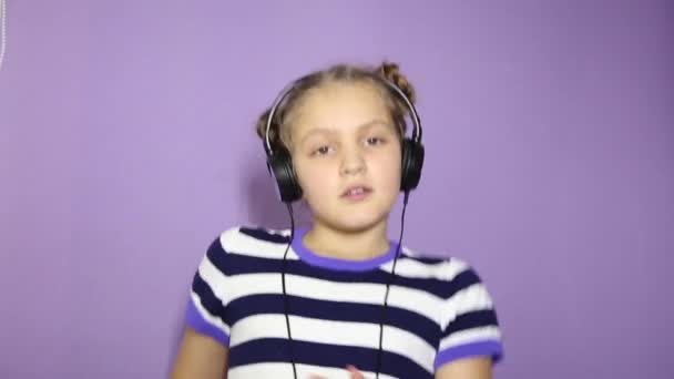 Niña con coletas escuchando música en los auriculares y bailando — Vídeo de stock