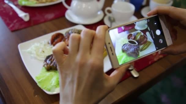 时尚女人在一家餐馆让食物照片与社会网络的手机摄像头 — 图库视频影像