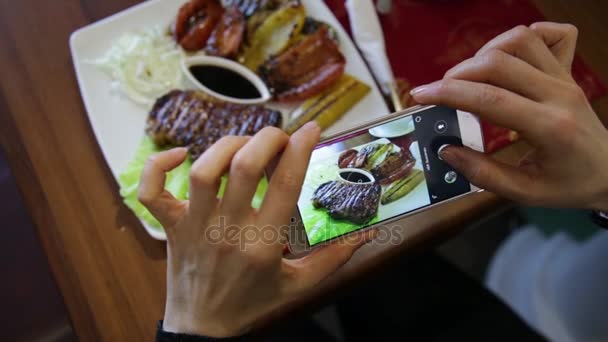 Trendy woman in a restaurant make photo of food with mobile phone camera for social network — Stock Video