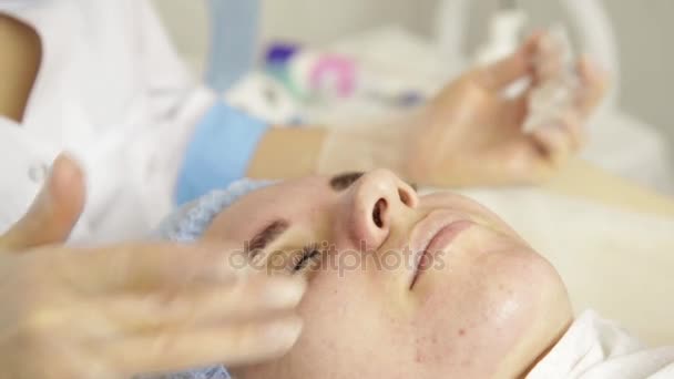 Schöne Frau mit kosmetischer Behandlung im Wellness-Salon. Kosmetikerin im Medizinhandschuh, berührt Mädchen im Gesicht. — Stockvideo