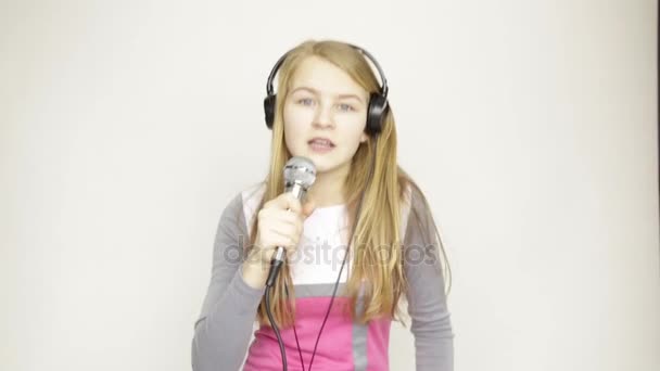 Young girl listening music on headphones holding microphone, singing and funy dancing — Stock Video