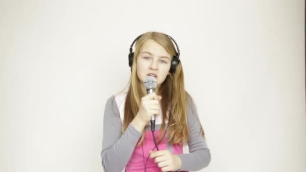 Niña escuchando música en auriculares sosteniendo micrófono, cantando y bailando funy — Vídeo de stock