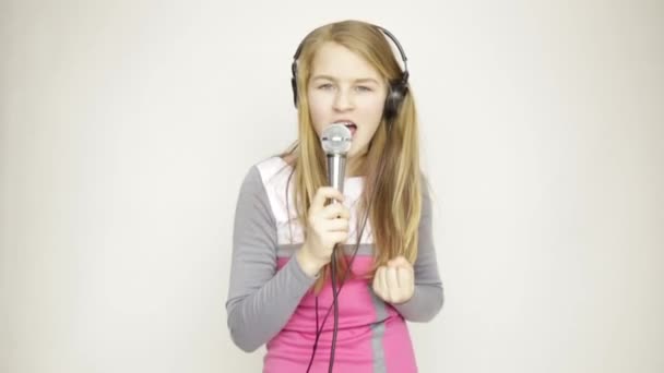 Молодая девушка слушает музыку на наушниках с микрофоном, поет и веселые танцы — стоковое видео