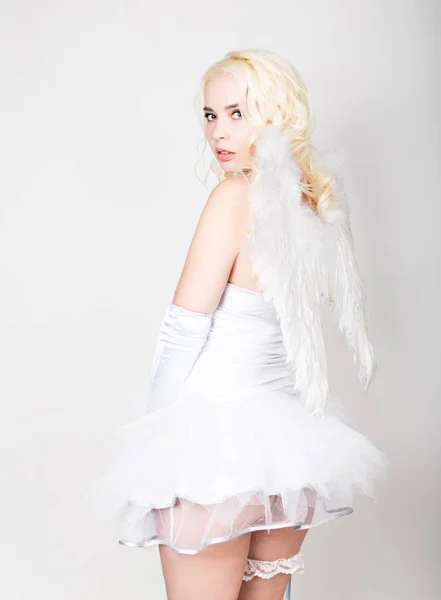 Bella sposa bionda vestita di bianco con trucco professionale e acconciatura, ali dietro — Foto Stock
