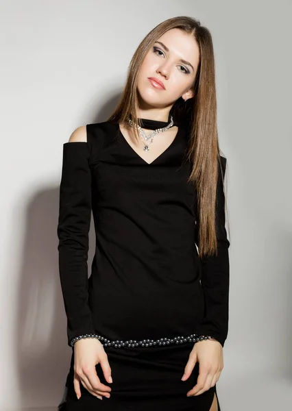 Negocio de la moda hermosas mujeres jóvenes en un pequeño vestido negro, sostiene cuentas de perlas —  Fotos de Stock