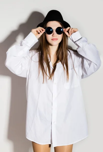 Chica desnuda en una camisa blanca mans, gafas de sol y sombrero negro — Foto de Stock