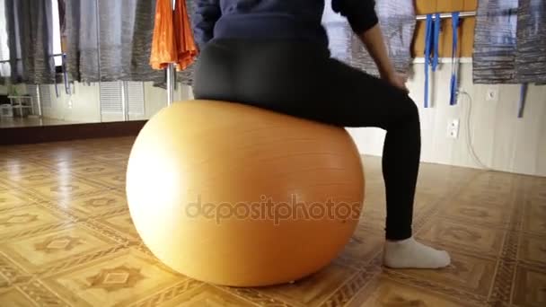 Schöne Fitness-Frau mit durchtrainiertem Körper, die auf dem Fitnessball sitzt und Übungen macht. Zeitlupe — Stockvideo