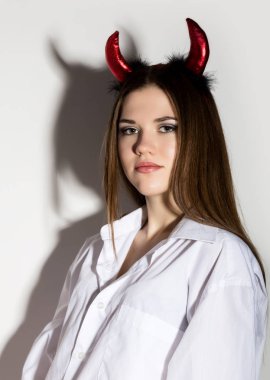 genç kız bir beyaz gömlek Kırmızı boynuzları trident tutan adamın ve güzel şeytan gibi görünüyor