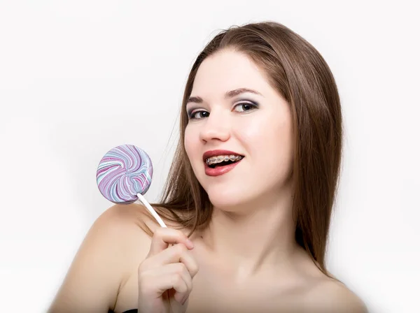 Retrato de adolescente mostrando frenos dentales y sosteniendo dulces — Foto de Stock