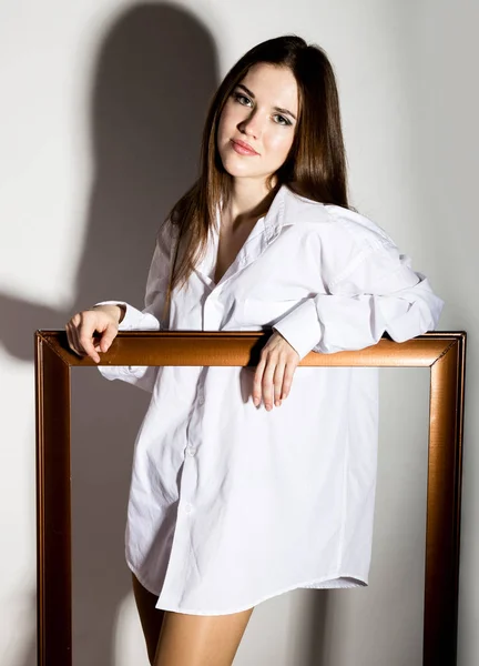 Menina nua em um homem camisa branca segurando moldura de madeira — Fotografia de Stock