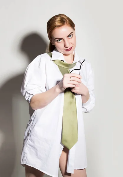 Meztelen fiatal nő egy mans fehér inget, zöld nyakkendő, gazdaság glasess, és mosolyogva — Stock Fotó