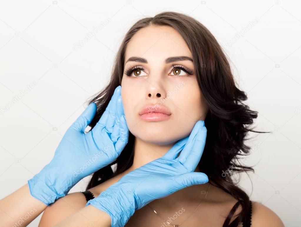 Closeup of Beautiful young woman gets injection in eye and lips area from beautician. cosmetology concept