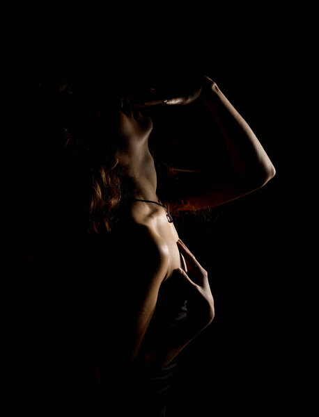 Elegant curves of female shoulders and neck, Redhead girl on a dark background.