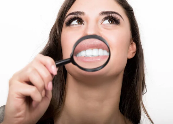 Portrait of young woman showing teeth and tongue through magnifying glass — Stock Photo, Image