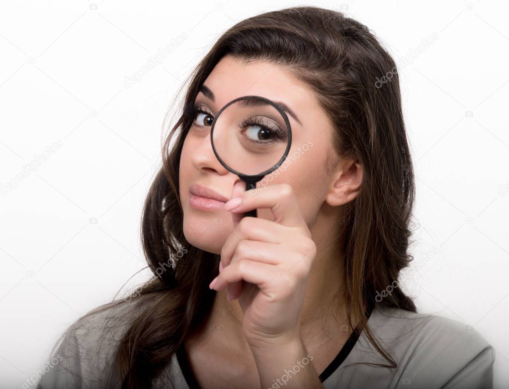 portrait of young woman looking through magnifying glass