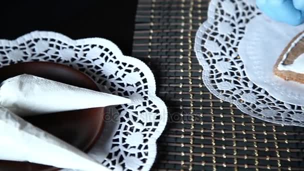 Vrouwelijke handen decoreren peperkoek kous met poedersuiker met behulp van zelfgemaakte spuitzak — Stockvideo