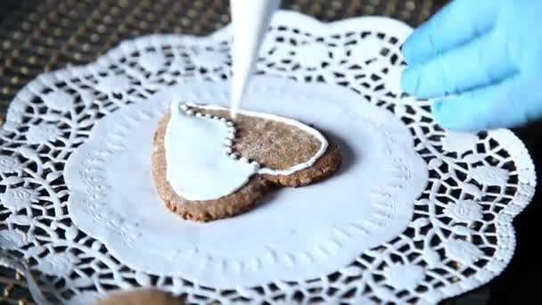 Manos femeninas que decoran la media de pan de jengibre con azúcar glaseado usando una bolsa de pastelería hecha a sí misma — Vídeos de Stock