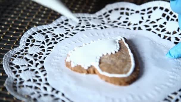 Manos femeninas que decoran la media de pan de jengibre con azúcar glaseado usando una bolsa de pastelería hecha a sí misma — Vídeo de stock