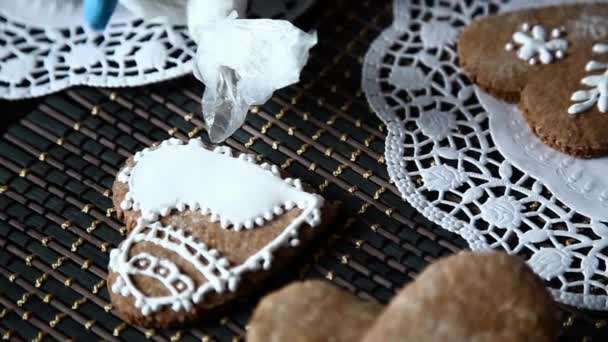 Manos femeninas que decoran la media de pan de jengibre con azúcar glaseado usando una bolsa de pastelería hecha a sí misma — Vídeos de Stock