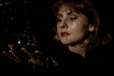 bir bardak su ile kaplı şeffaf cam arkasında poz şarap olan gizemli kadın bırakır. karanlık bir arka plan üzerinde